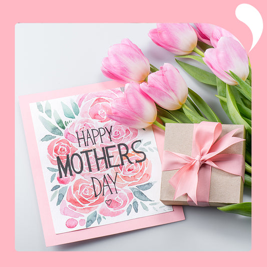 A table is set with Mother's Day cards, gift boxes, and a bouquet of flowers.