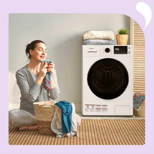 The woman's eyes are closed as she feels the wash next to a comfee washer and dryer.