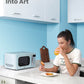 a woman is drinking orange juice and eating chicken wings with a microwave oven next to her