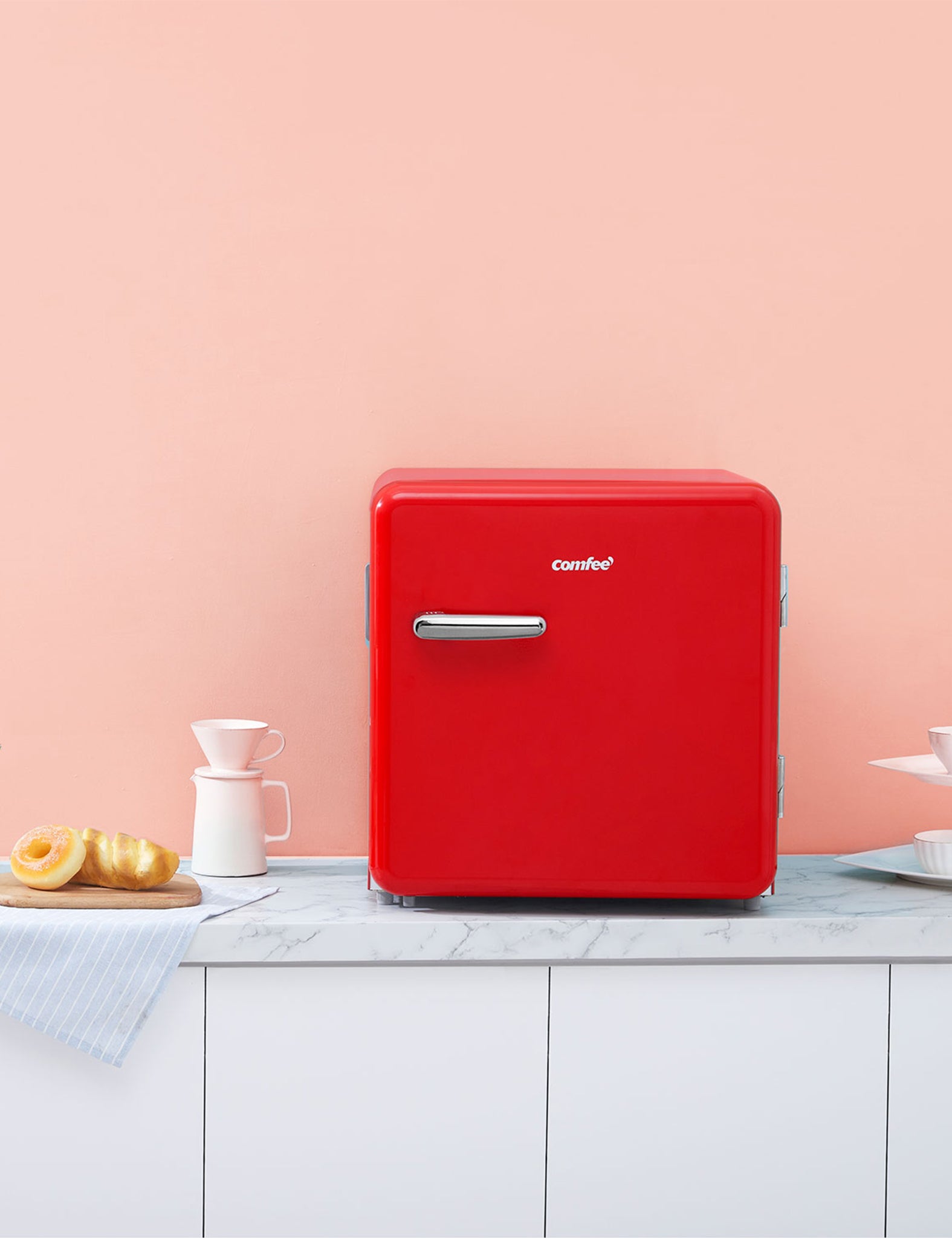 mini red retro style fridge sitting on a cabinet next to a plate of donuts
